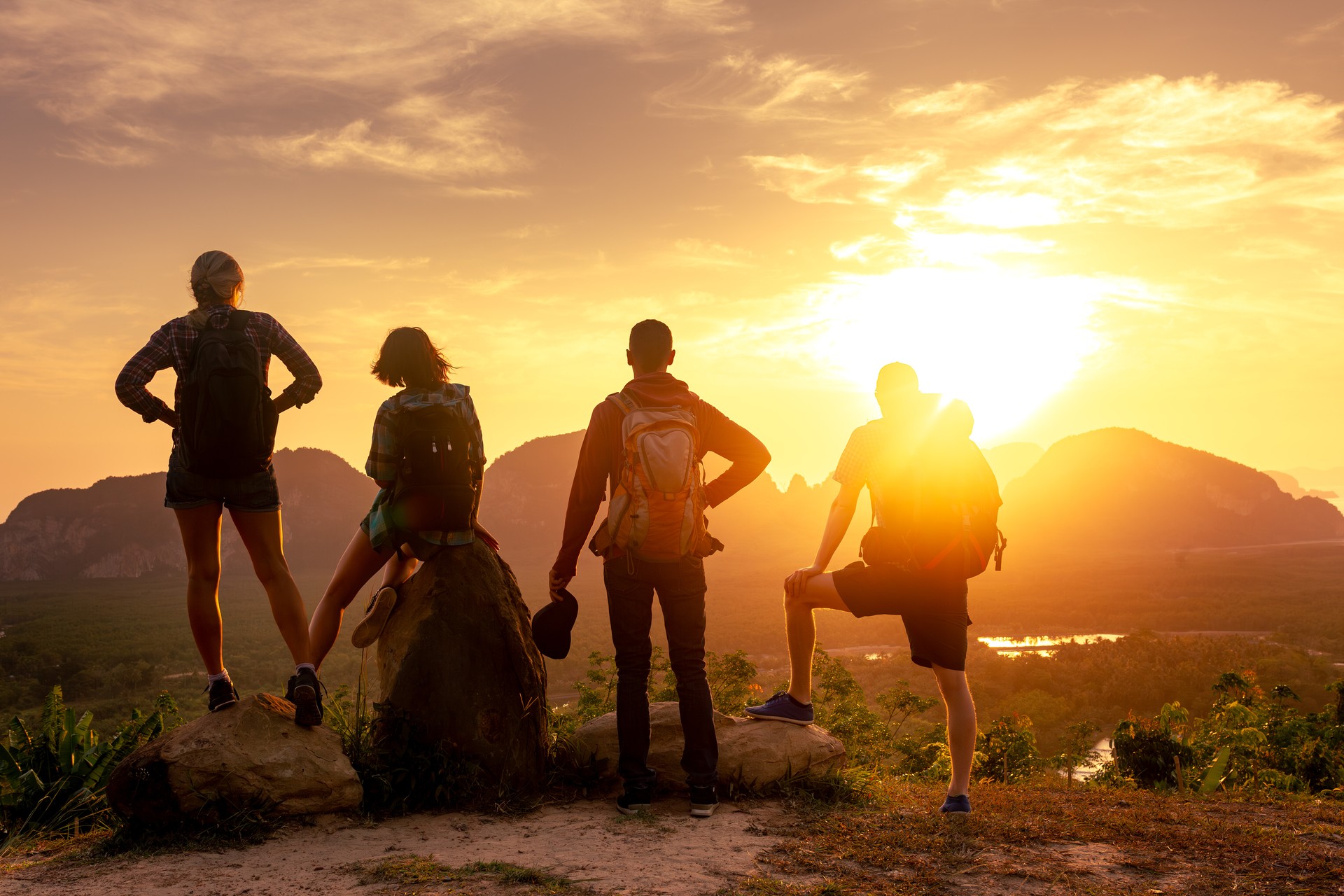 Four young friends are enjoying sunrise, sea and islands