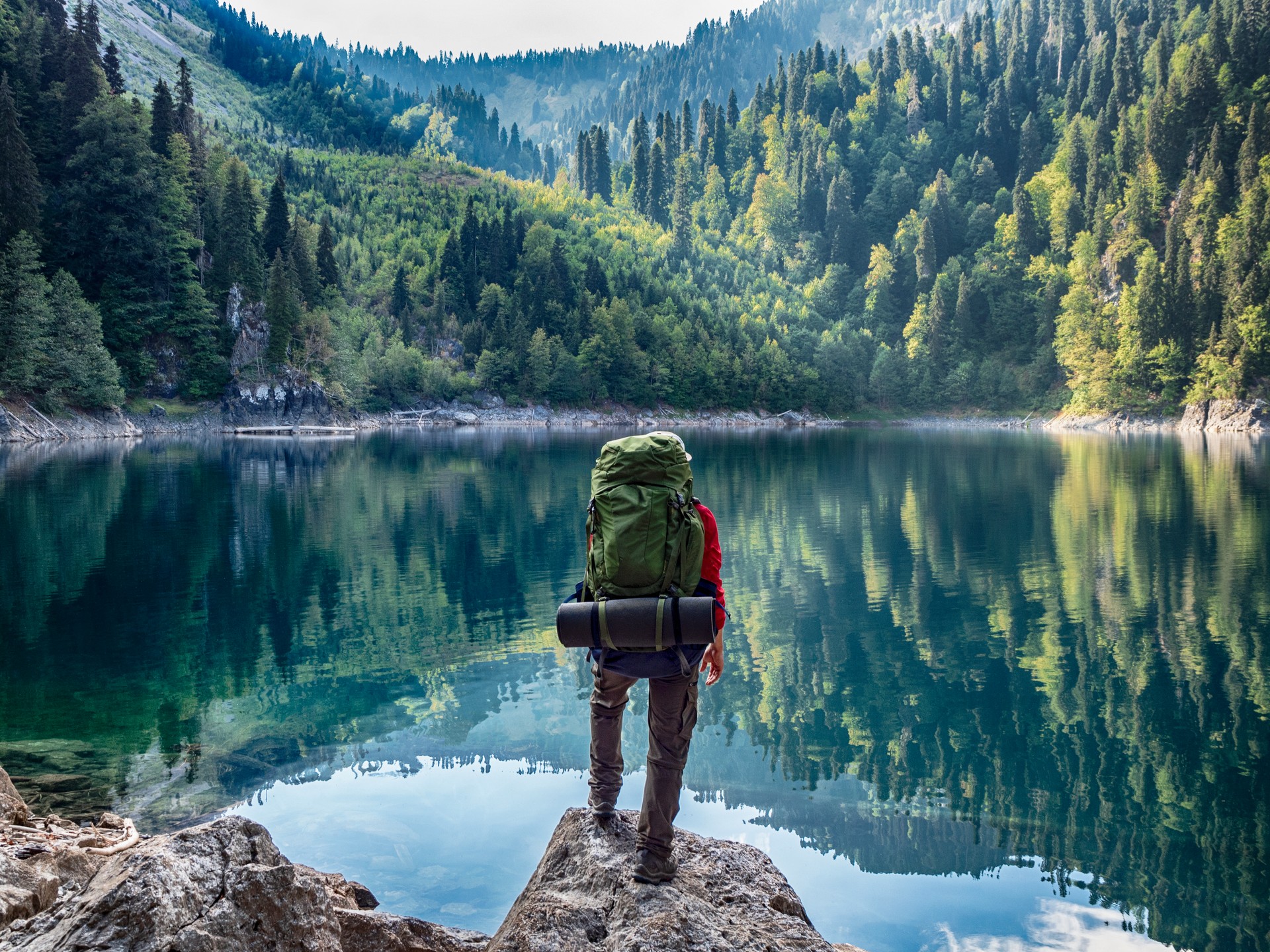 Tourist with backpack at mountain lake background